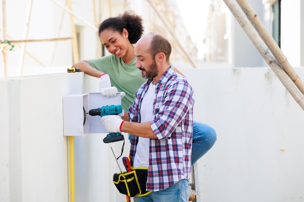 working outdoors hispanic male electrician engineer installer with tool his hands young black woman couple maintenance service repair handyman concept 38052 2987